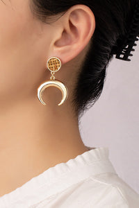 Metal horn drop earrings topped by a woven rattan disk